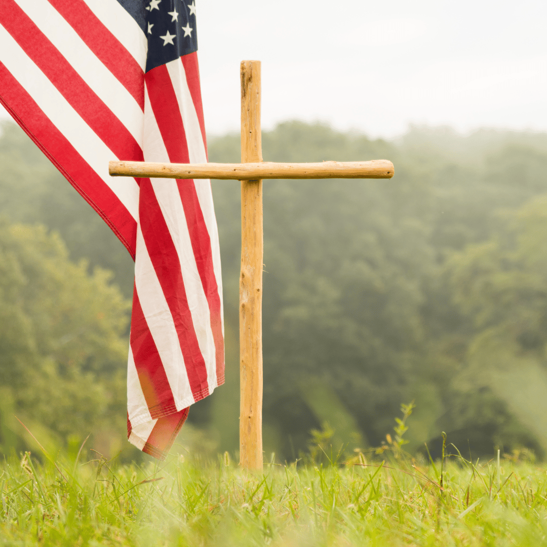 A cross in a field with the American flag. 
