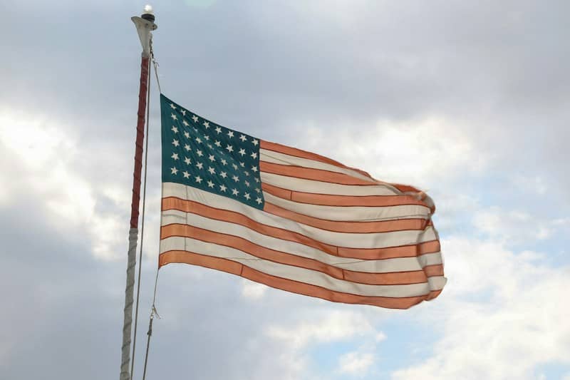 The American flag waving on a pole against a cloudy sky