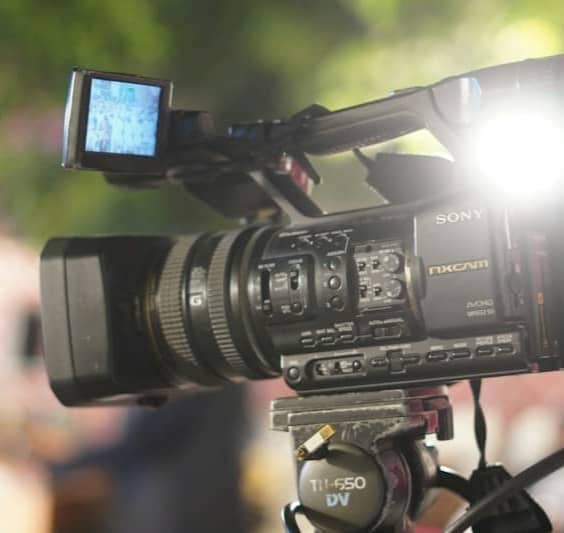A professional video camera with a bright light mounted on a tripod