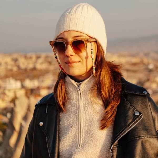 A woman wearing a hat and sunglasses standing in front of hot air balloons