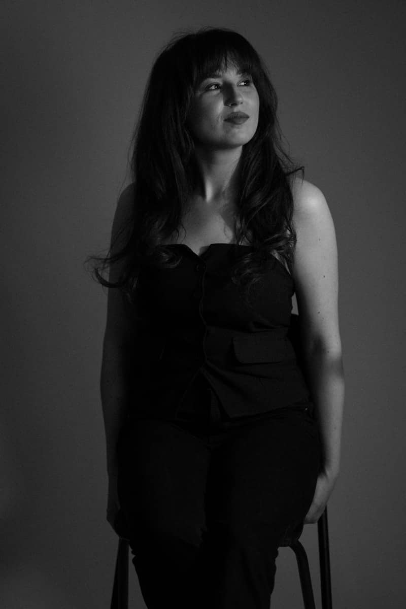 A woman poses pensively in black and white.