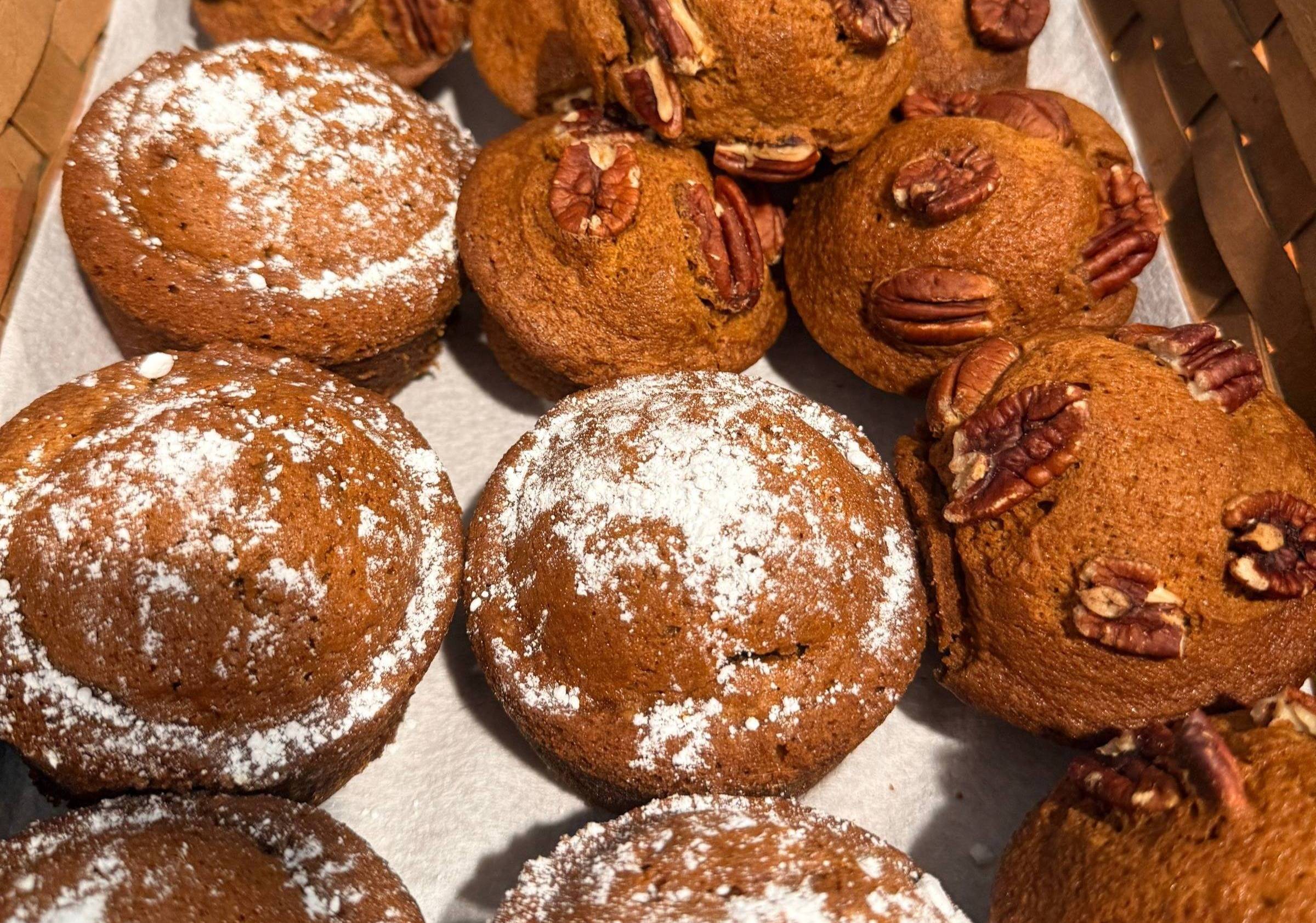 Pumpkin muffins dusted with powdered sugar and topped with pecans
