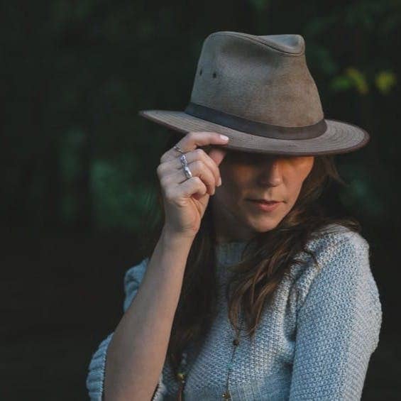 woman in blue sweater holding her hat