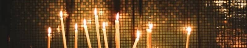 Many lit candles glowing in the dark