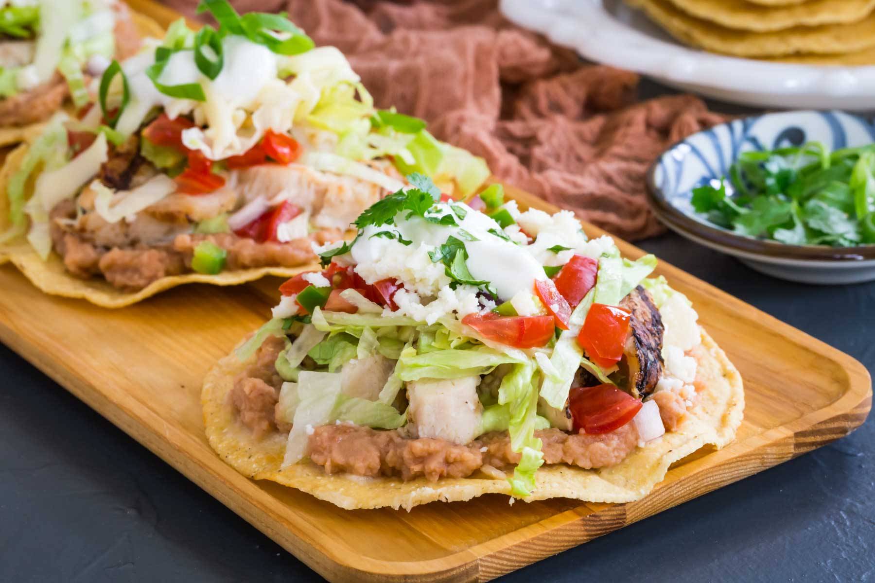Chicken tostadas on a wooden platter.