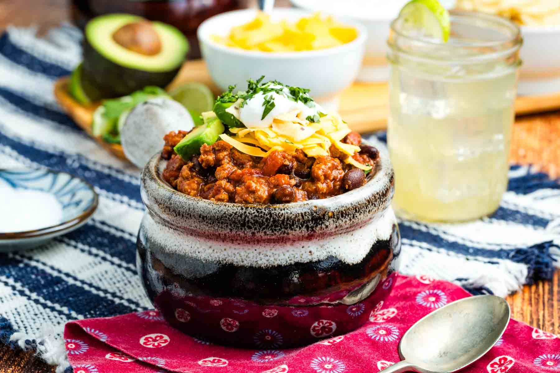 Turkey chili in a crock topped with cheese and sour cream.