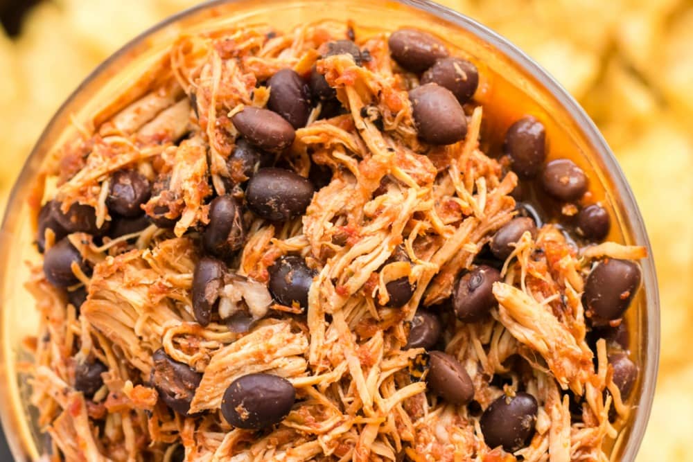 A bowl of shredded salsa chicken with black beans.