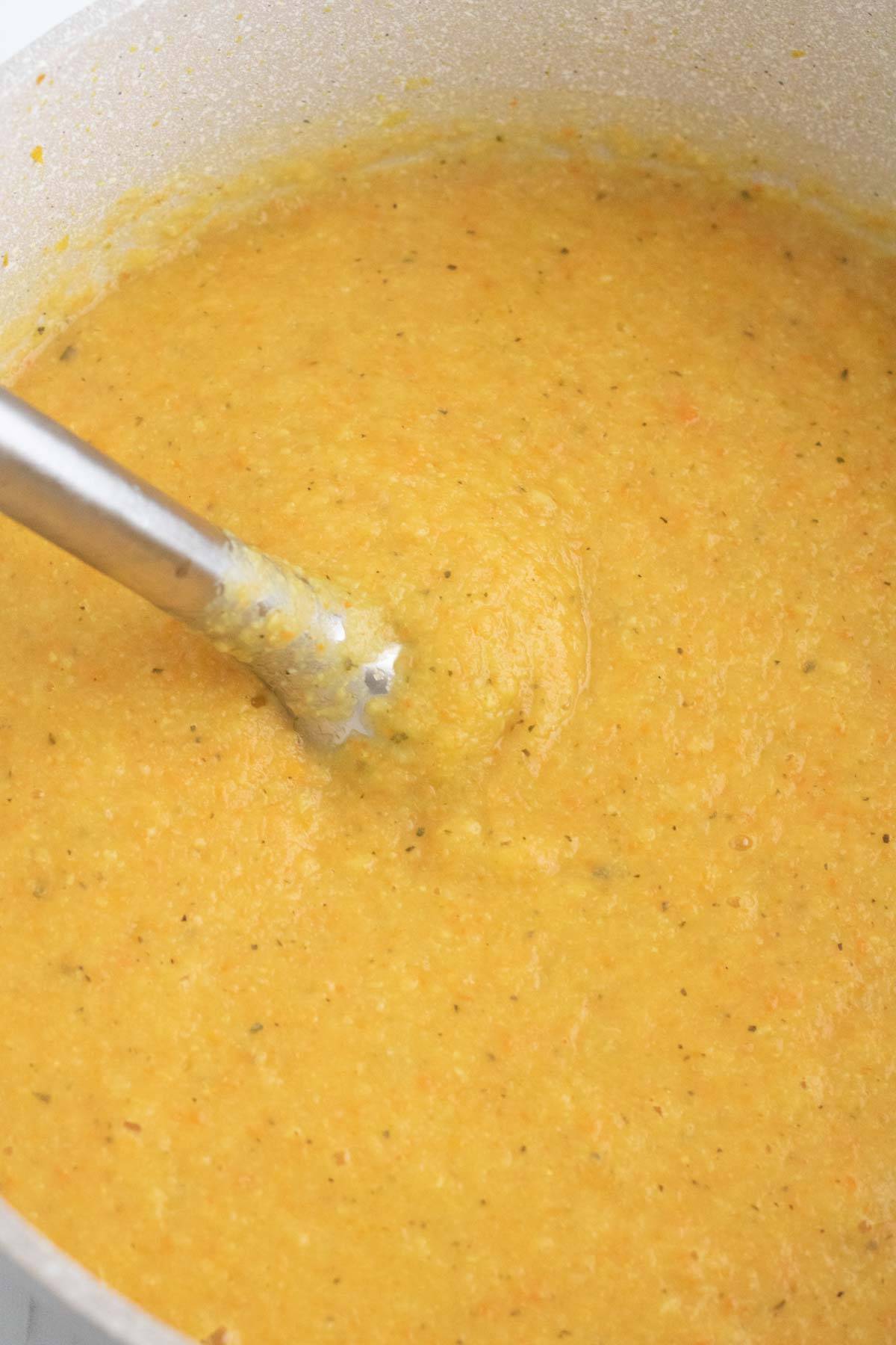 An immersion blender in a pureed soup
