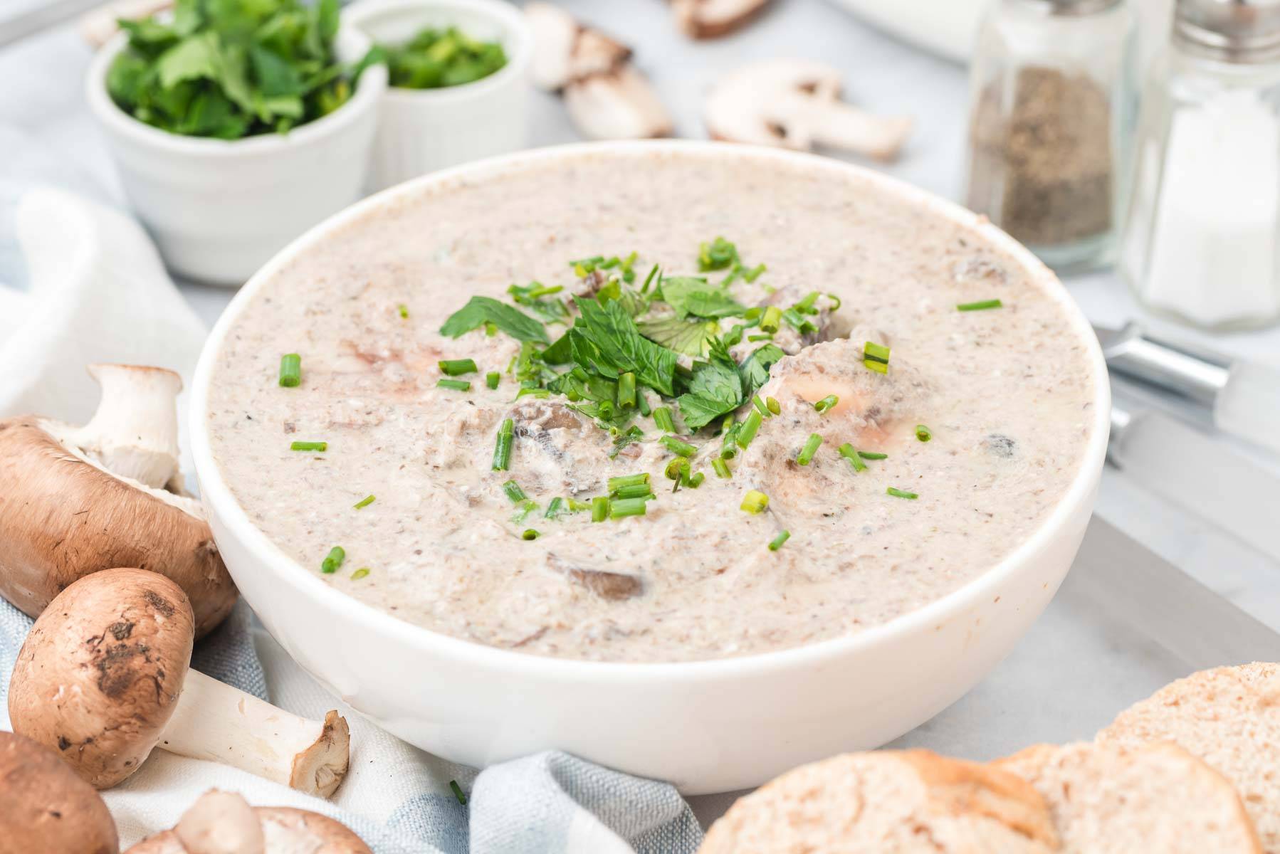 A bowl of cream of mushroom soup garnished with parsley.