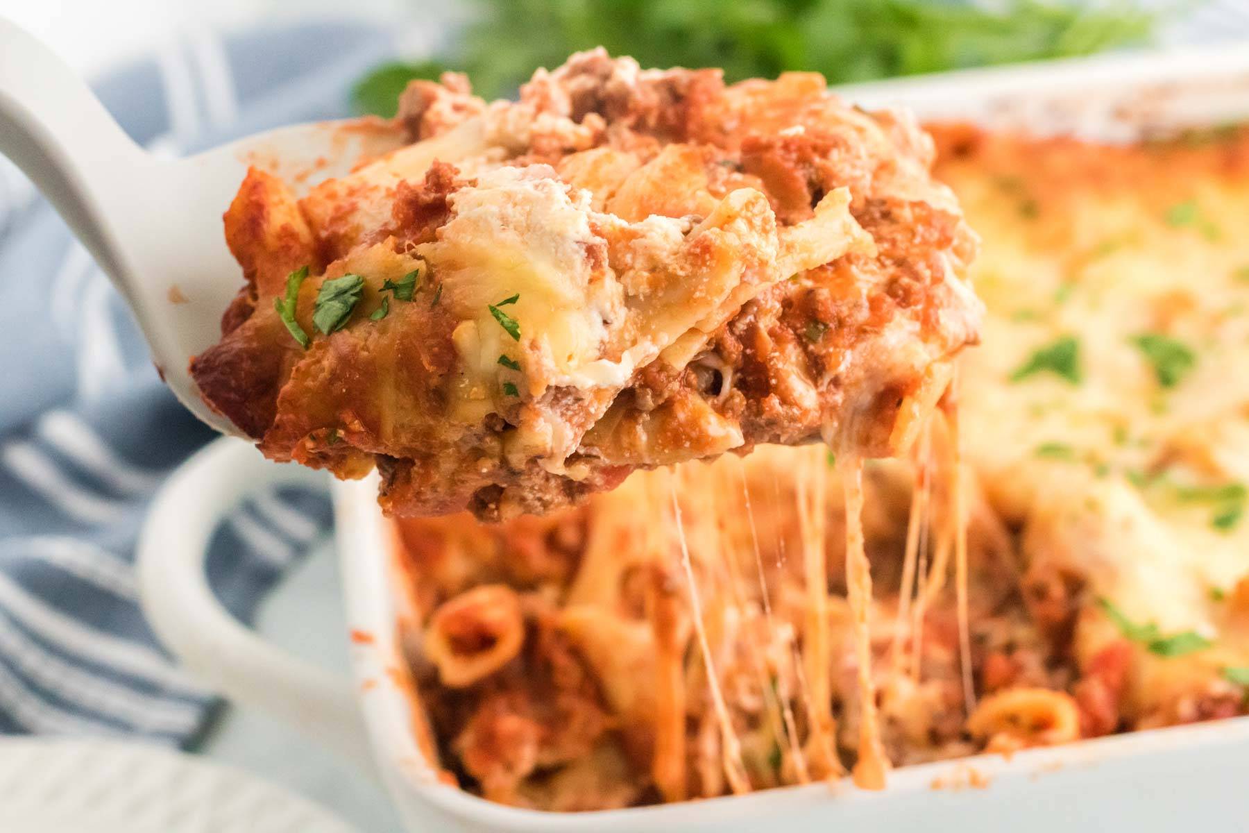 A spatula scooping up a serving of baked ziti.