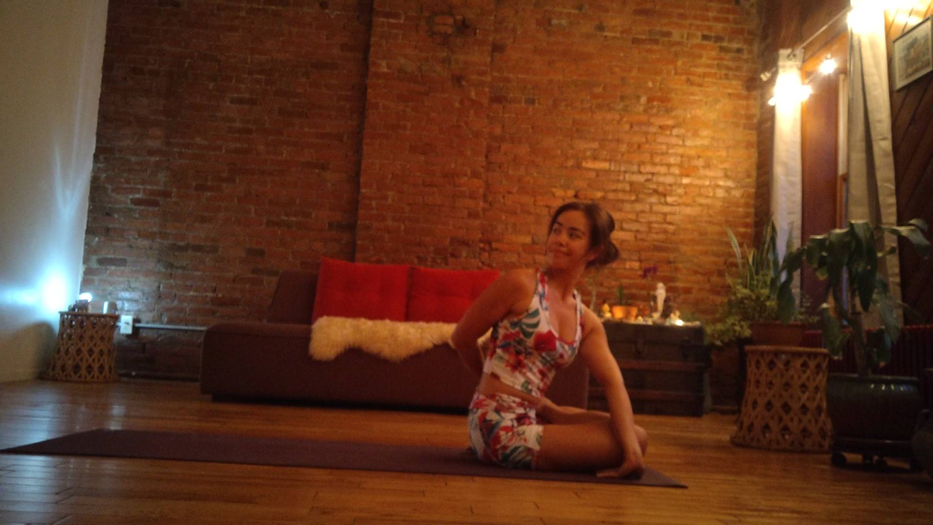 Shayna in a seated yoga posted in a warmly lit studio.