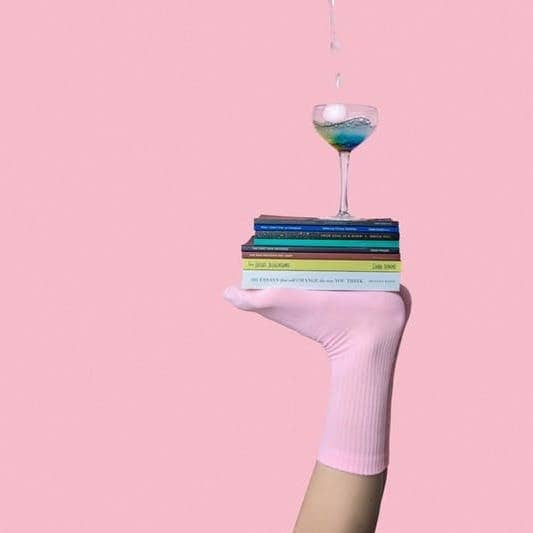 person balancing martini glass above book with feet