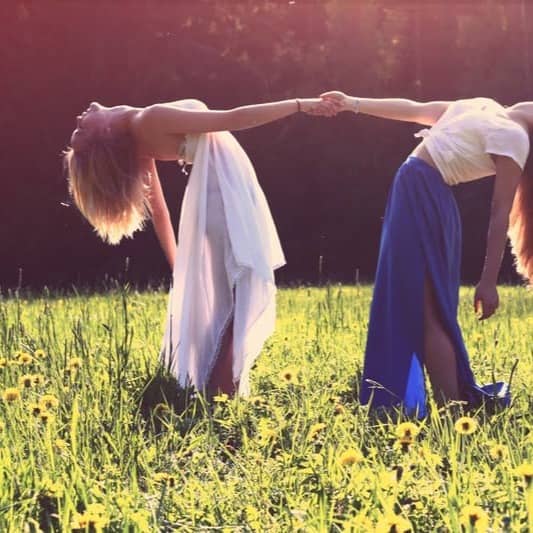 two women bending while holding hands