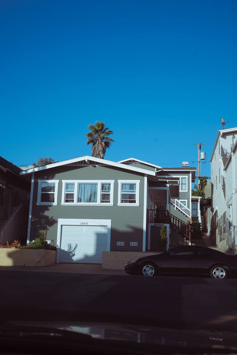 A house and a car under a blue sky.