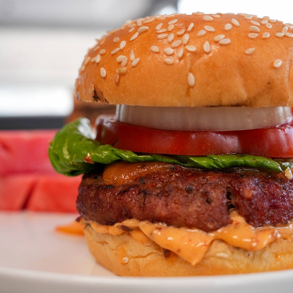 A smoked hamburger with lettuce, tomato and onion. 