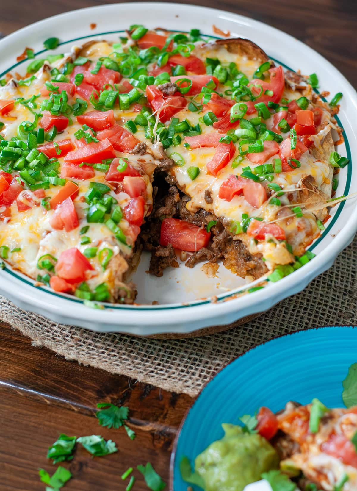 A top view of taco pie with a slice missing.  Showing cheese, tomatoes and ground beef. 
