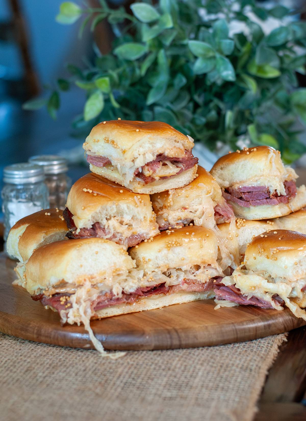 A stack for corned beef sliders, showing melted cheese, sour kraut all on toasted buns.   