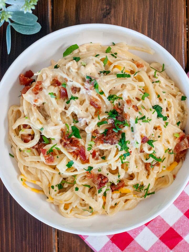 A top view of bacon ranch chicken showing pasta, creamy sauce, bacon bits and fresh parsley. 
