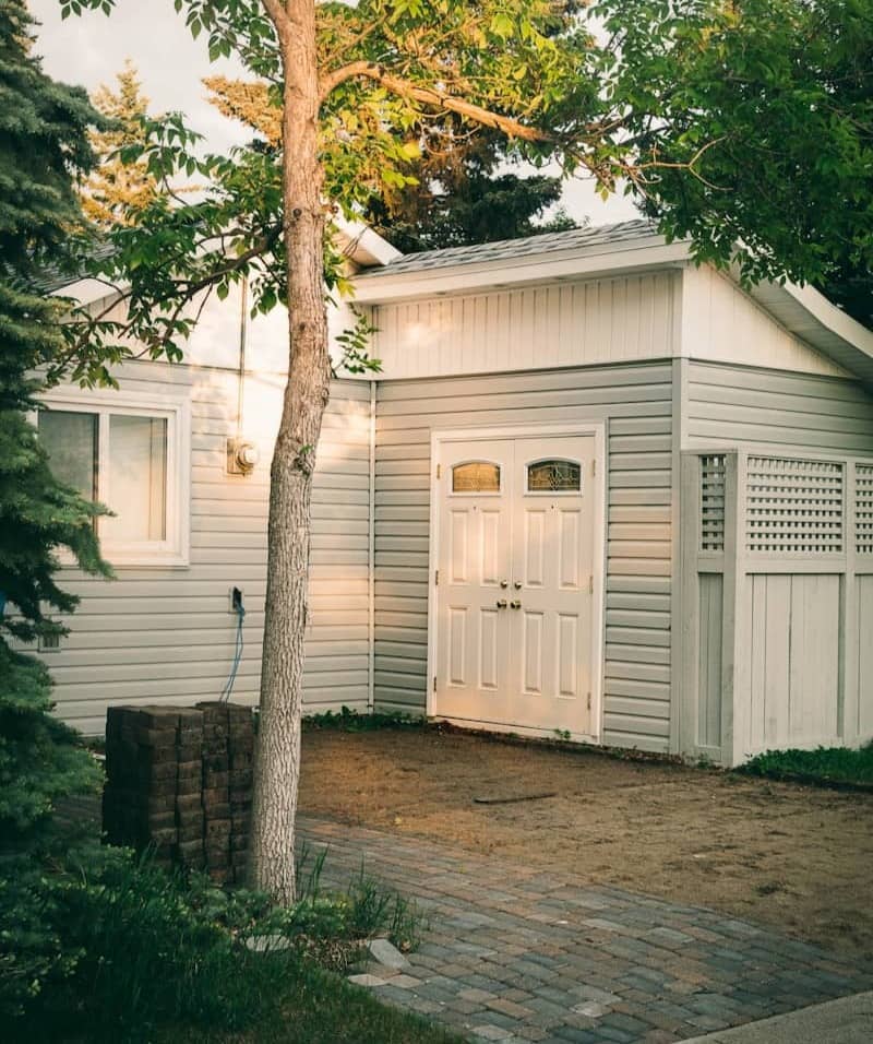 white wooden house near green tree during daytime