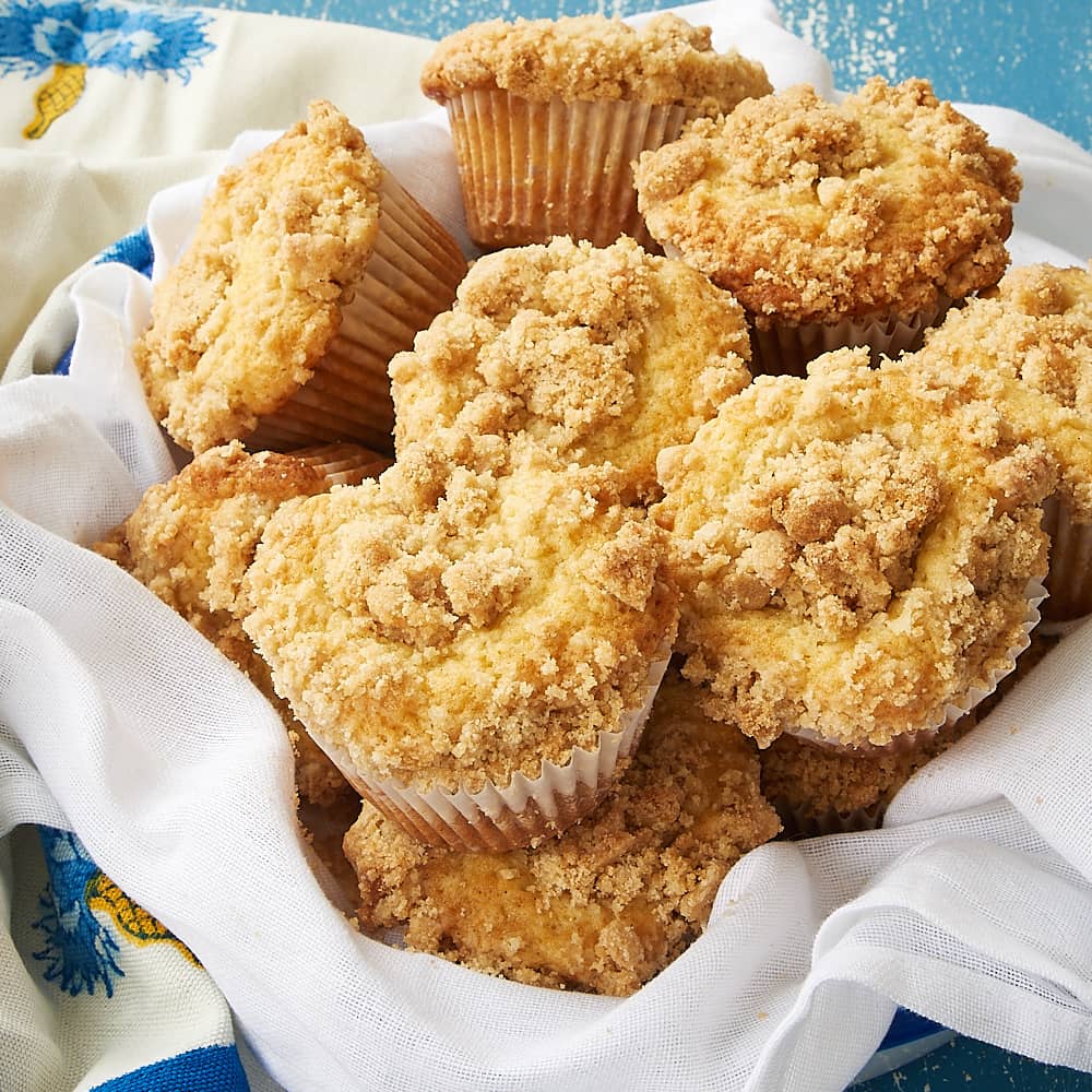 crumb-topped vanilla muffins in a towel-lined basket
