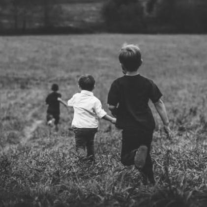 three boys running on field