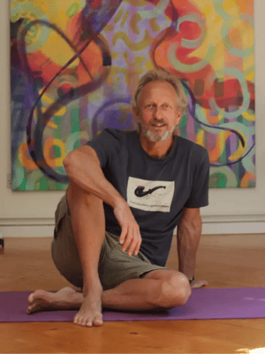 erling mccracken yoga teacher sat relaxed on a mat smiling to camera