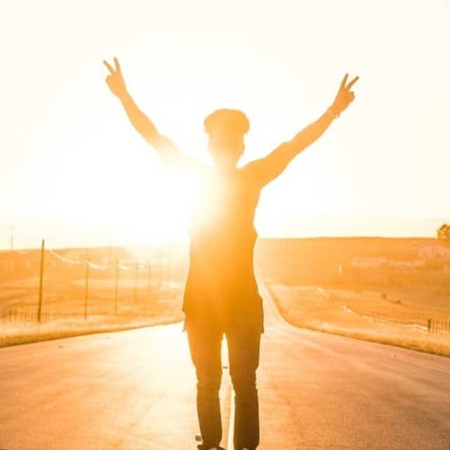 person raising both hands doing peace sign hand gesture on road during daytime