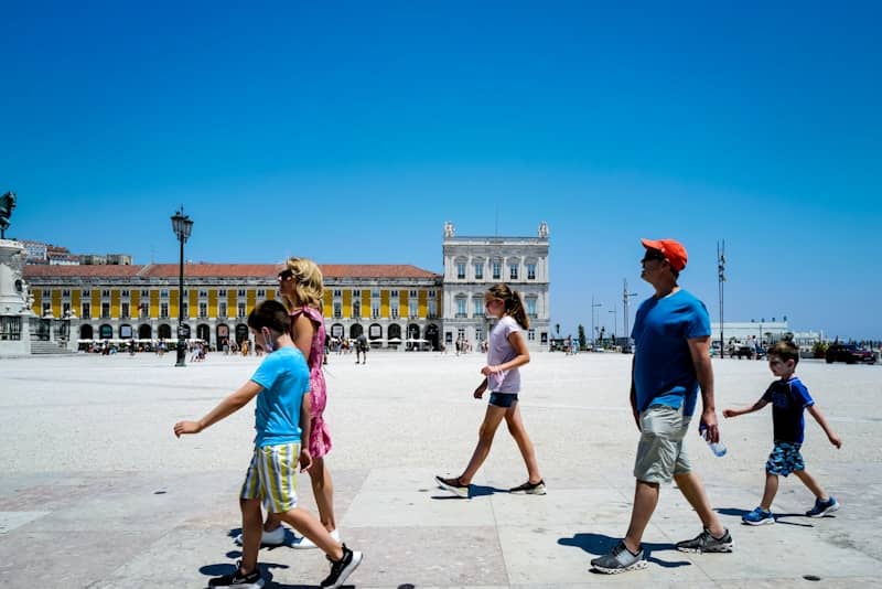 A family walks across a sunny, open square.