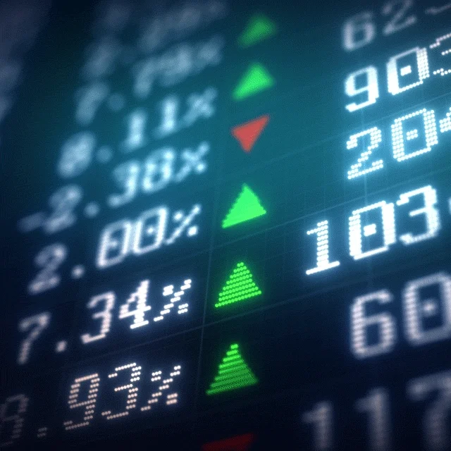 A black market board with green and red triangles next to white numbers that indicate how much a stock's price has increased or decreased