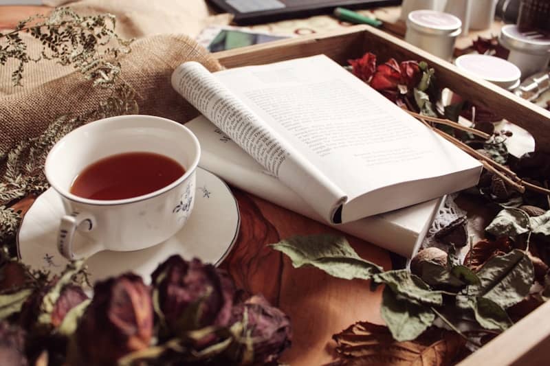 A cup of tea and books on a wooden tray
