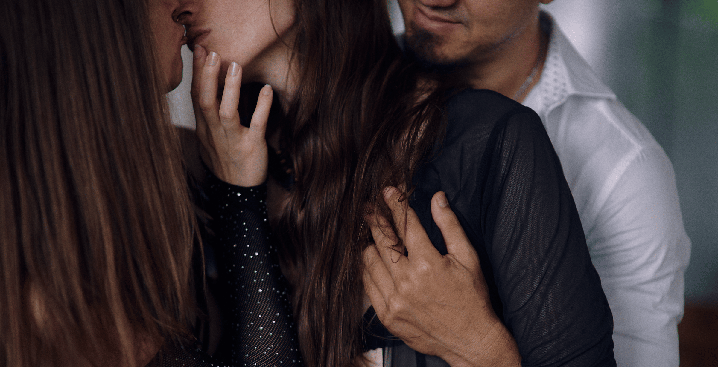 Elaine Love kissing a woman, while her partner hugs her from the back