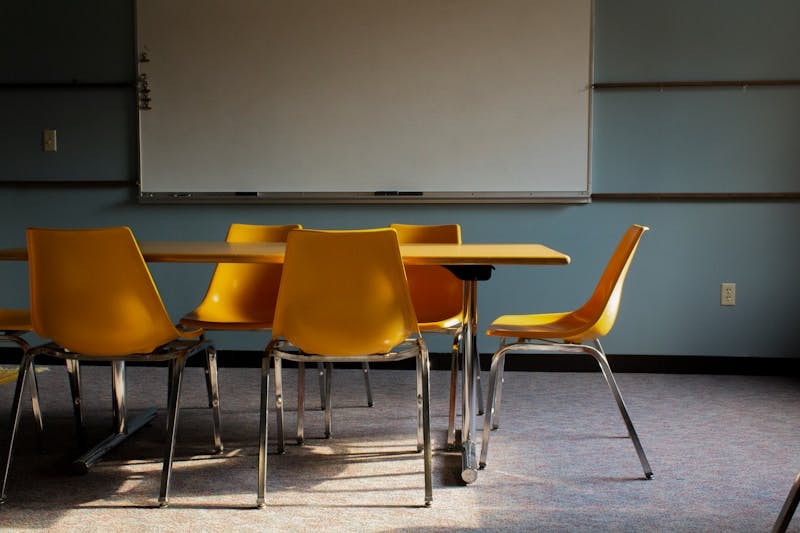 A classroom with a whiteboard and yellow chairs