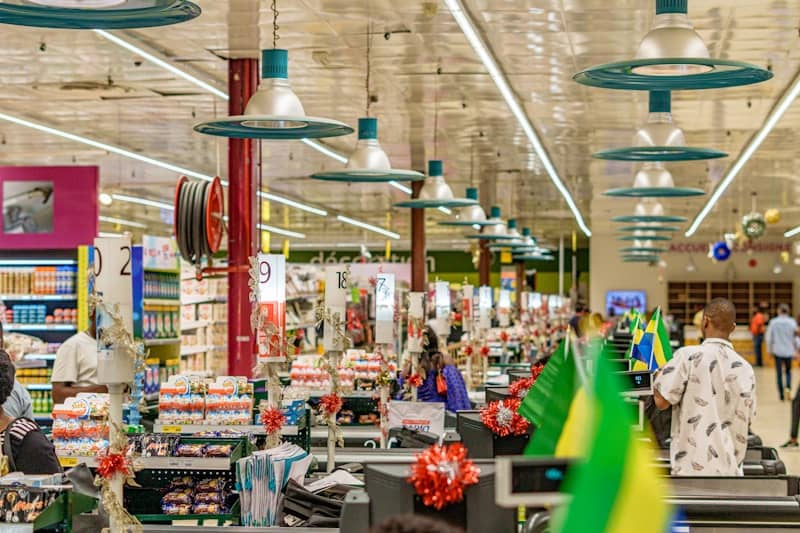 People shopping in a brightly lit supermarket aisle.