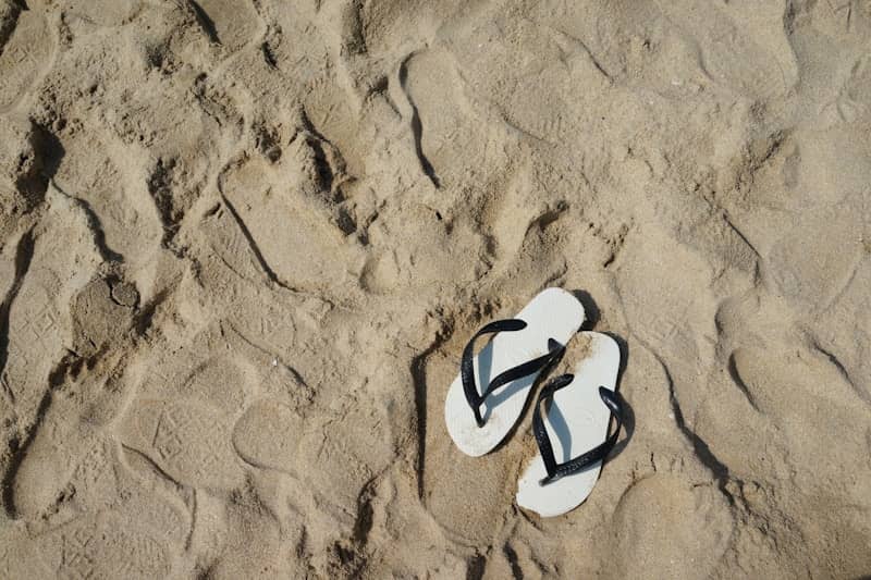 White flip-flops resting on sandy beach