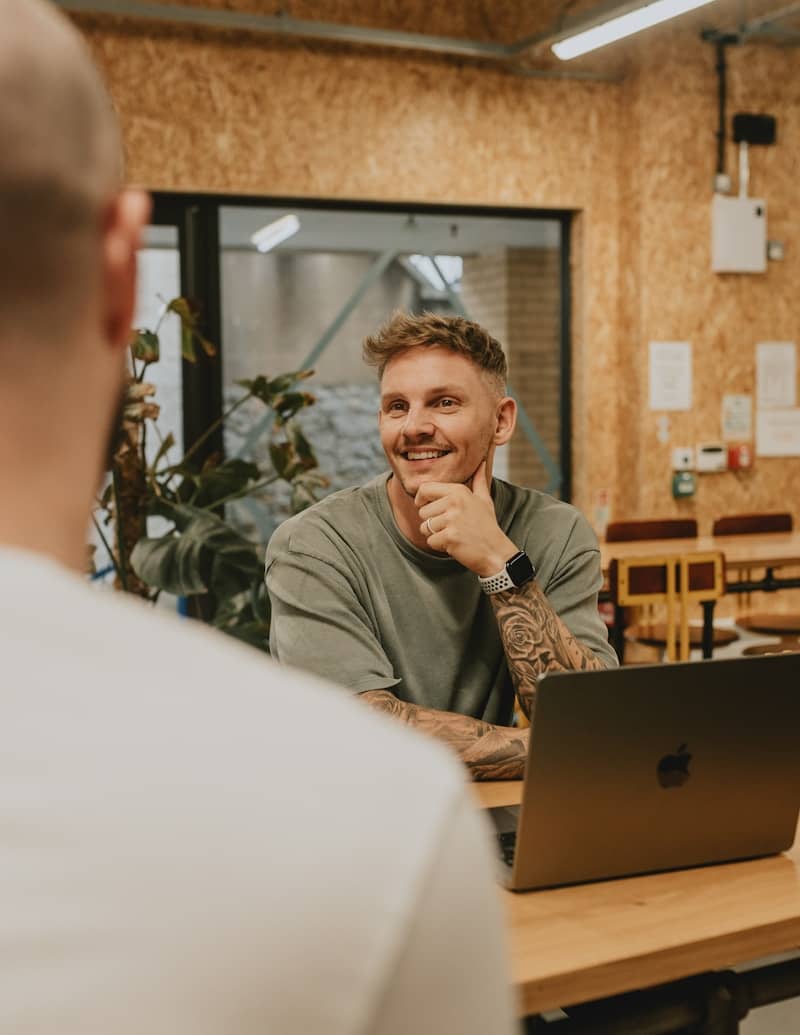 A man smiles while talking to someone.