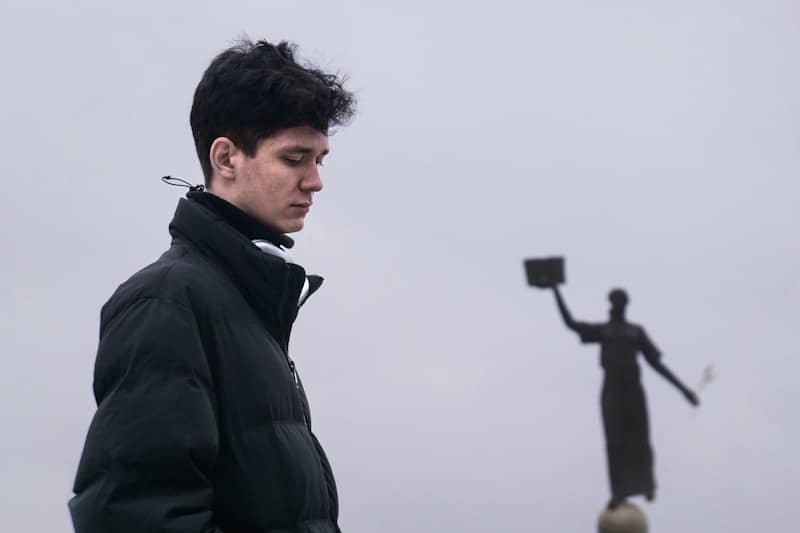 A man standing next to a statue holding a frisbee