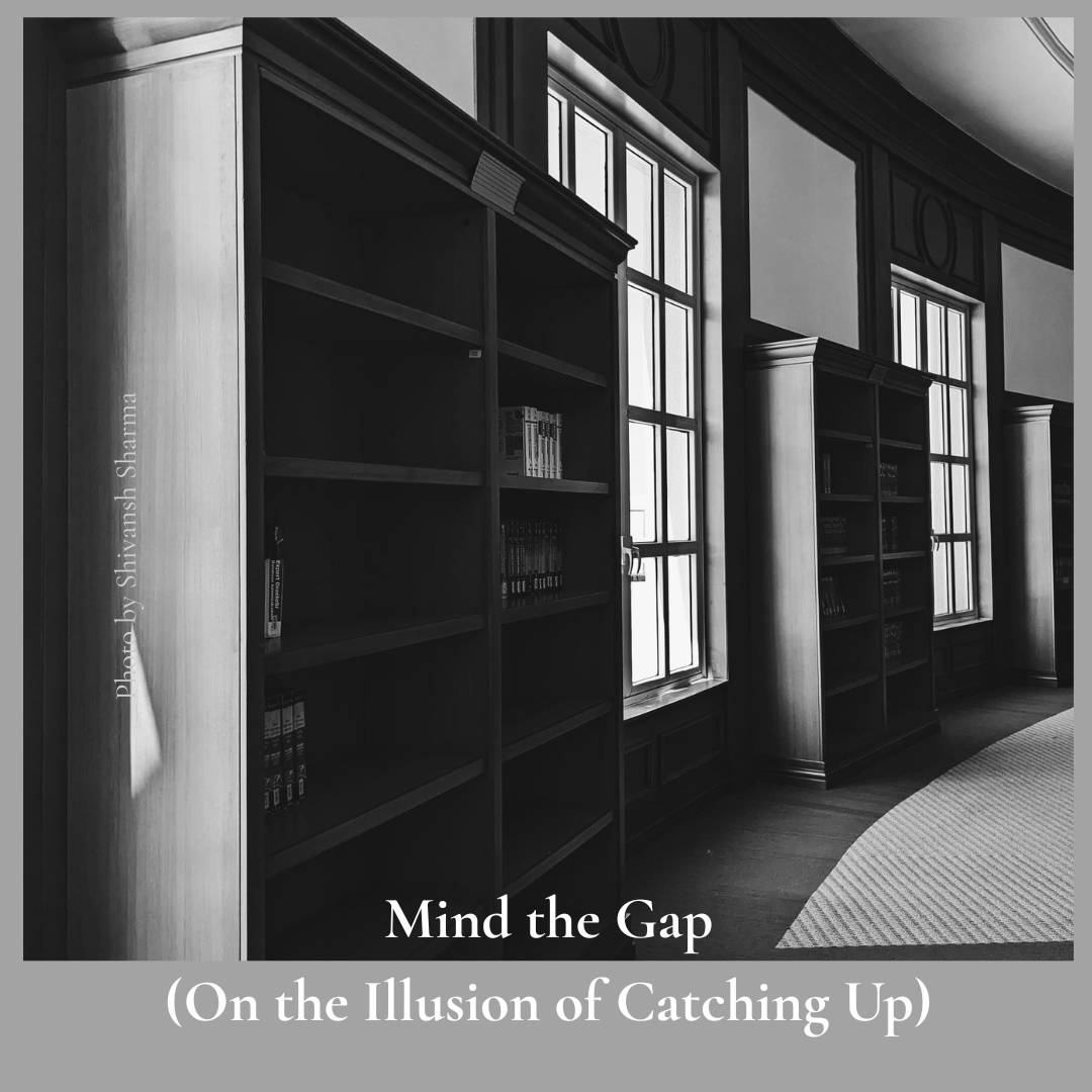 A black and white image of mostly empty library shelves next to tall multi-panewindows