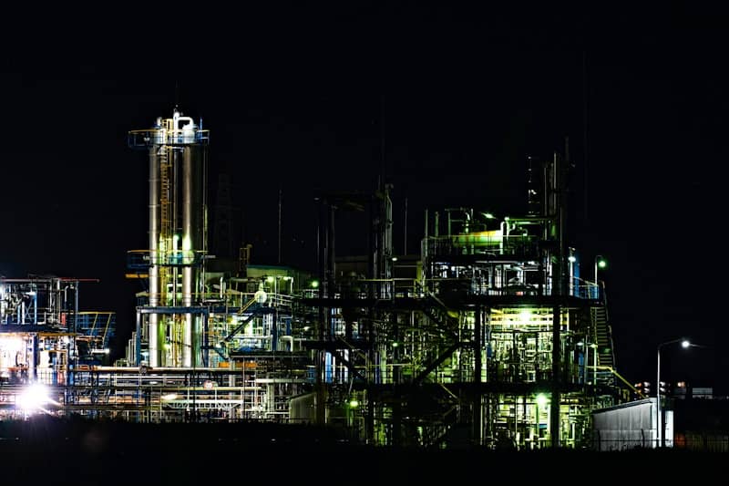Industrial complex illuminated at night against dark sky