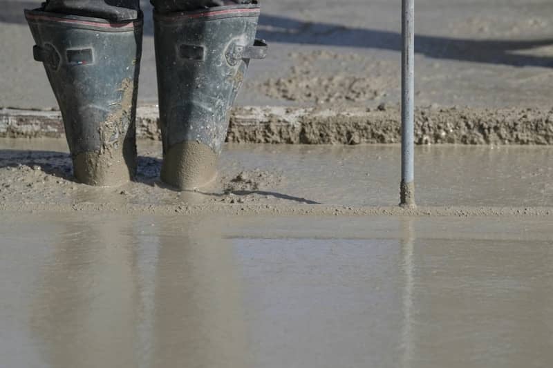 Worker's boots standing in wet concrete.