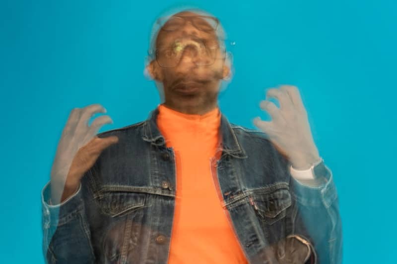 a man wearing a jean jacket and orange shirt