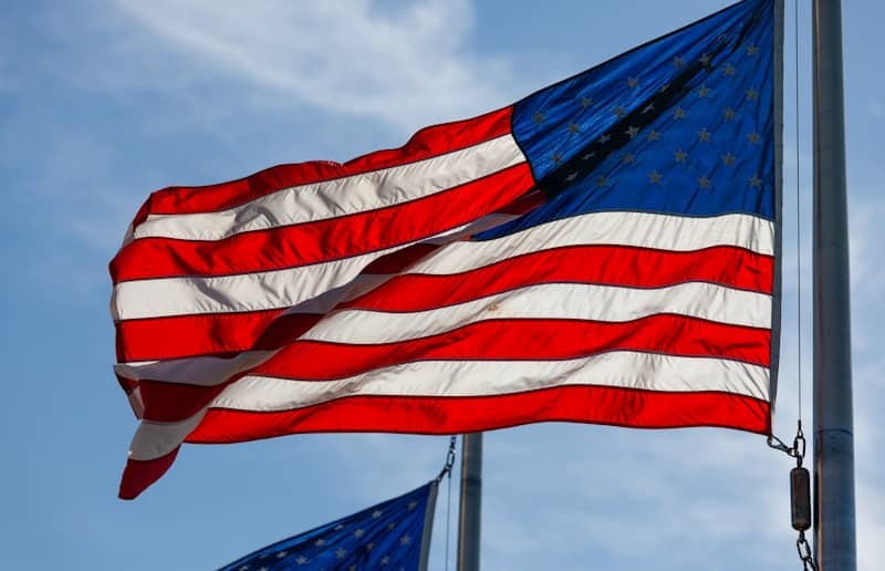 An american flag waving against a clear blue sky.