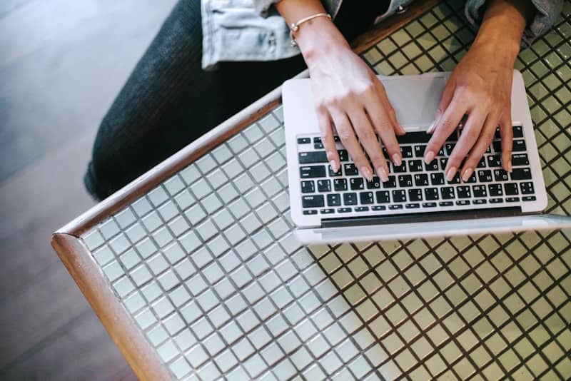 Person types on a laptop on a checkered table.