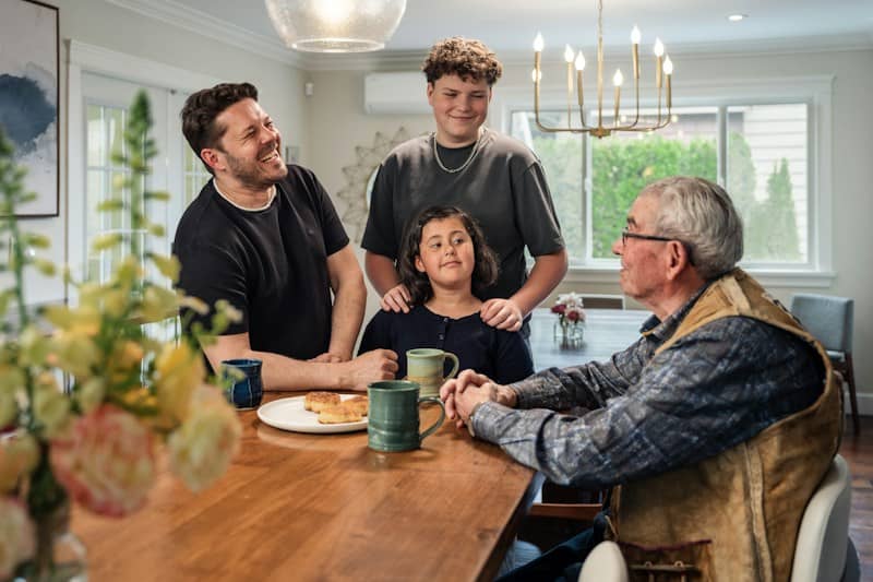 A family of four gathered around a wooden dining table in a bright room