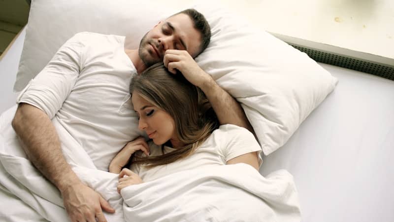 Couple sleeping peacefully in bed together.