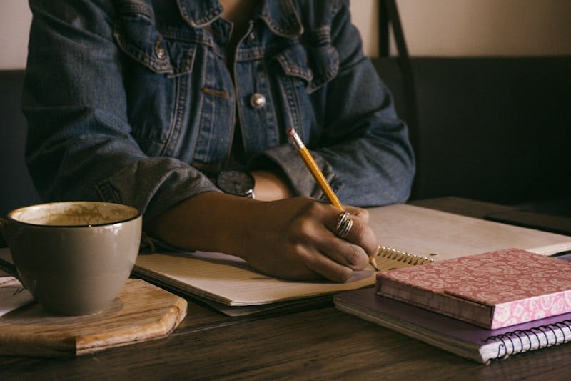 woman writing on paper inside well-lit room