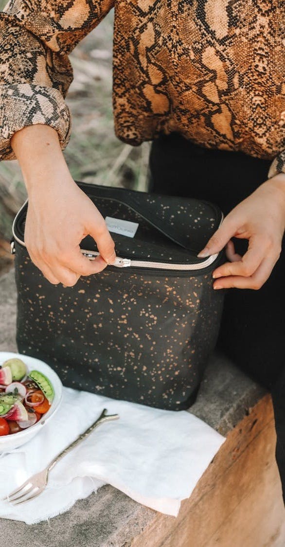 woman opening lunch bag near bowl of salad