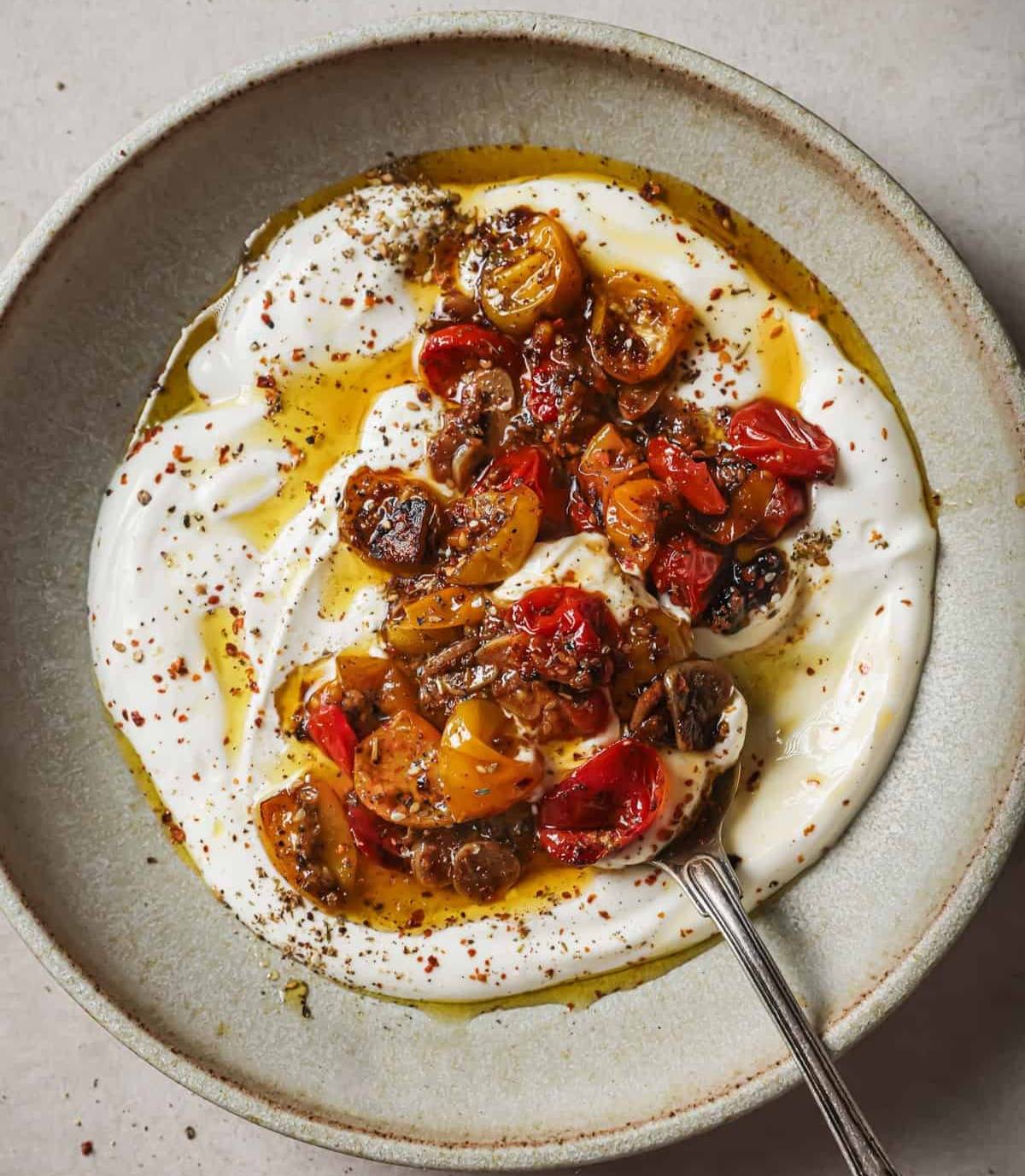 vegan yogurt, spices and confited tomatoes with their oil in a bowl.