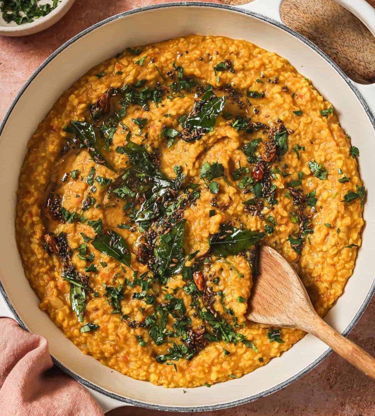 finished dal tadka in a deep saucepan with a wooden spoon.