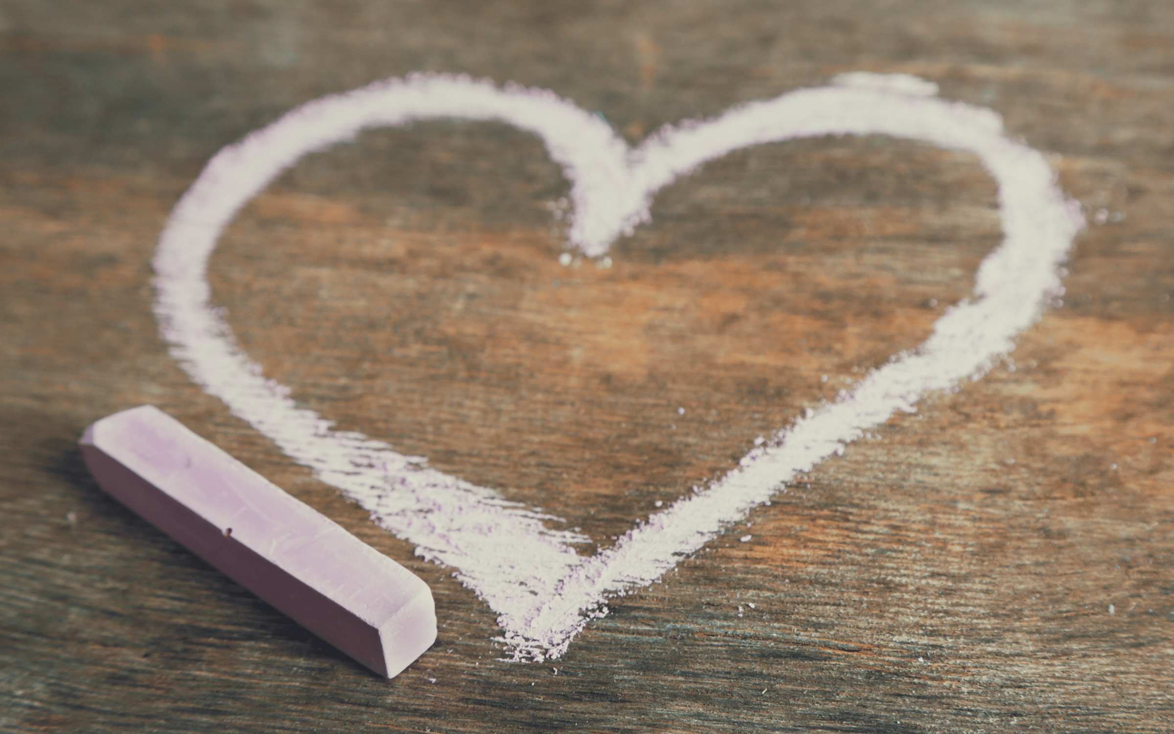 Pink chalk heart drawn on a wood slab