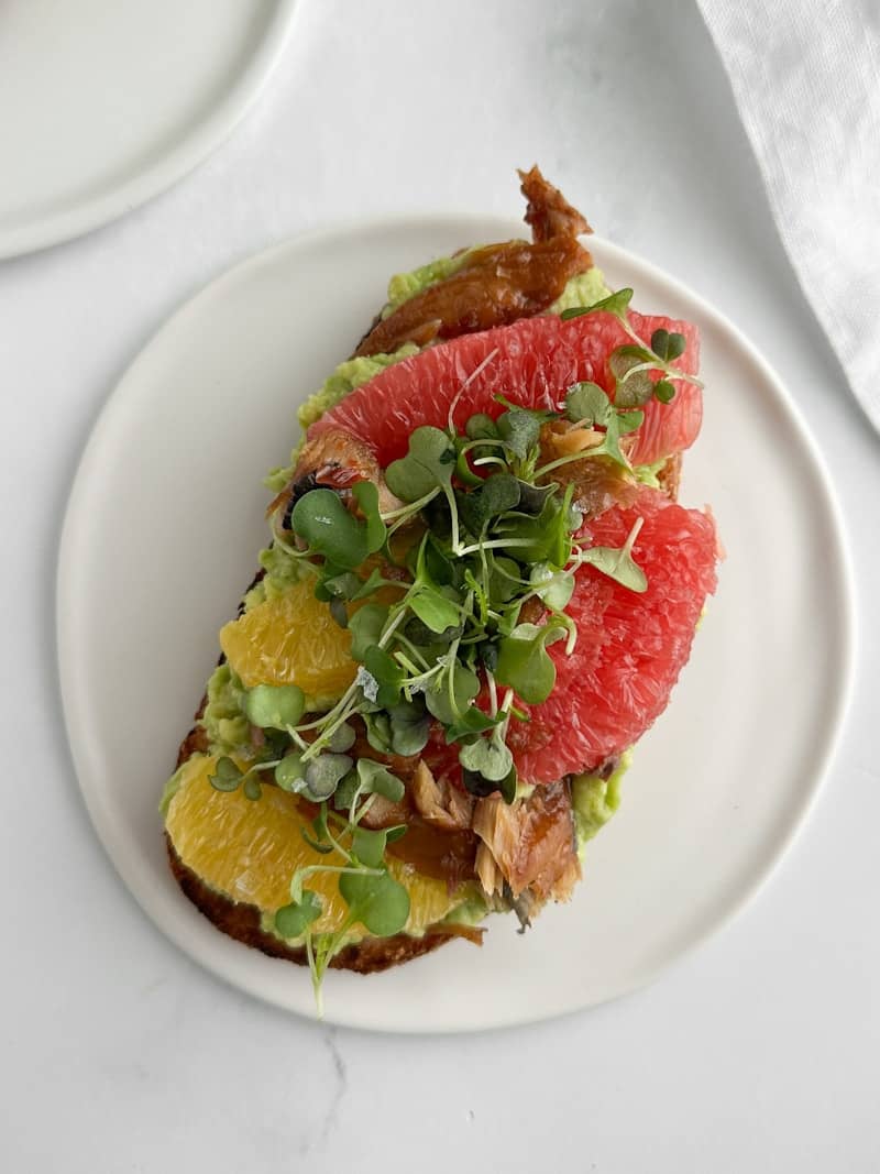 Avocado toast with grapefruit, orange, and sprouts